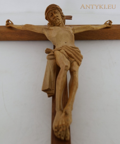 drewniana figura Jezusa z rozłożonymi ramionami i rzeźbioną szatą – ujęcie od dołu