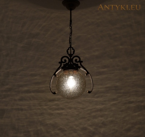 zapalona lampa na łańcuchu i wzór światła oraz cieni na ścianie